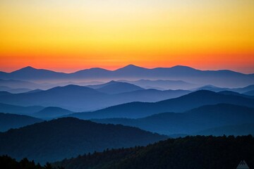 Expansive mountain range silhouetted by warm sunset colors, vast clear sky with three-quarters focus, delicate orange and yellow hues 3