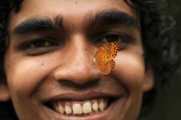 Butterfly sitting on a young man’s face, Symbiosis of man and nature.