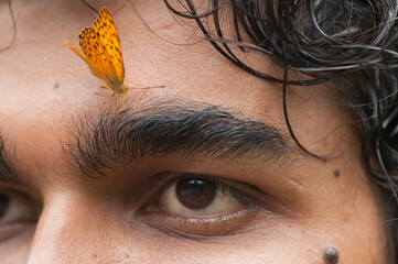 Butterfly sitting on a young man’s face, Symbiosis of man and nature.