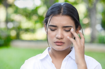 Indian office worker woman suffering from irritated eye, concept image for optical health care, red eye allergy, eye care, allergic or itching or dry eye inflammation