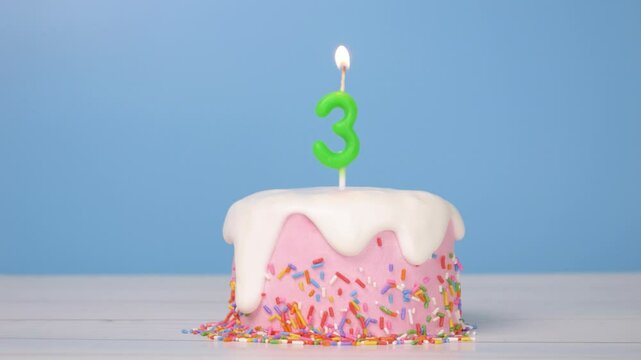 birthday cake with number three candle to celebrate 3rd birthday, seamless looping of cute cake with colorful candle number 3 for birthday annual celebrate party was lit, light blue background