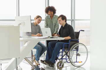 Teamwork brainstorm. Diverse multiracial colleagues man in chair for people with disability working...
