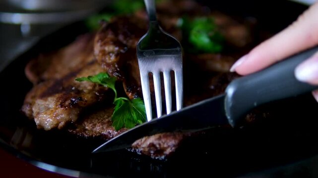 Close up shot of unrecognizable female chef pouring fresh green herb sauce over roasted meat served with asparagus and vegetables on plate meat steak. parsley cilantro grilled