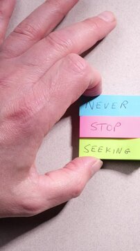 Truth seeking concept. Words Never Stop Seeking handwritten on colourful sticky notes on top of grey textured paper background.