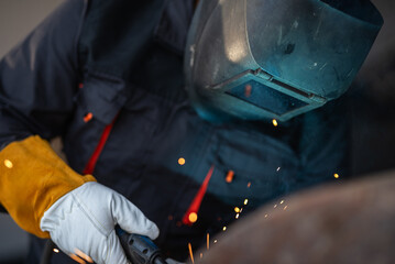 Industrial worker welding metal with sparks flying