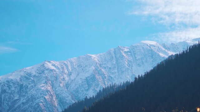 Clouds above the snowy Himalayan mountain peaks during a sunny day as seen from Triloknath village near Udaipur in Pattan Valley, Lahaul and Spiti district, Himachal Pradesh, India. Winter background.