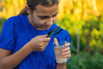 A child looks at water through a magnifying glass. Selective focus.