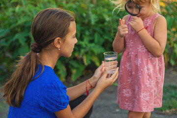 A child looks at water through a magnifying glass. Selective focus.
