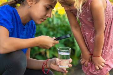 A child looks at water through a magnifying glass. Selective focus.