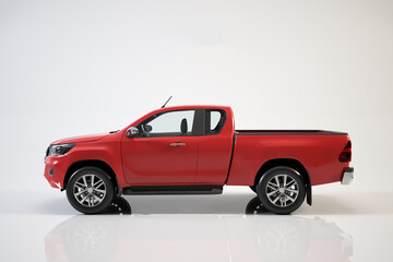 Red pickup truck sits on reflective surface in studio. © Waypixel
