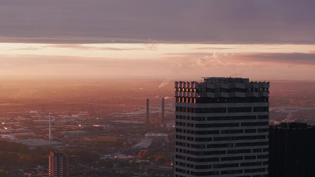 Establishing aerial view passing Croydon high rise residential blocks with hazy golden cityscape