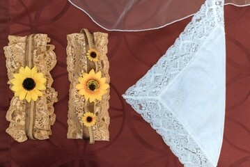 Bridal garters with sunflower accents on burgundy fabric