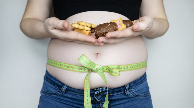 Obesity and overweight from overeating. Big belly tied with measuring tape as a gift. Body fat from candies and sweets