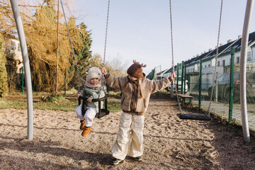 Happy smiling cute girls, preschooler female kids playing, sliding in kid playground with colorful...