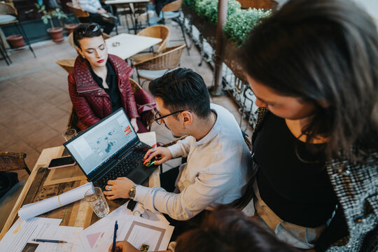 A diverse group of business people working together on a project at a coffee bar, engaging in discussion and brainstorming ideas. The image captures teamwork and collaboration in a casual setting.