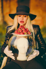 Glamorous woman in white gloves holding aquarium with mannequin man's head. Fashion concept.