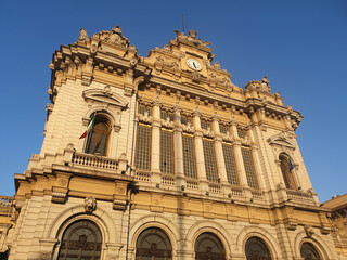 The grand facade of Genoa Piazza Principe train station illuminated by golden sunlight, showcasing its ornate architectural details and classical design.