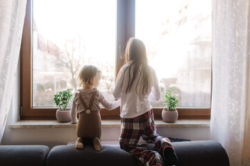 The child looks out the window while sitting in the house. No heating concept. Generation alpha concept