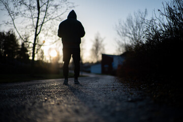 lonely man is walking on a street wearing a hoodie