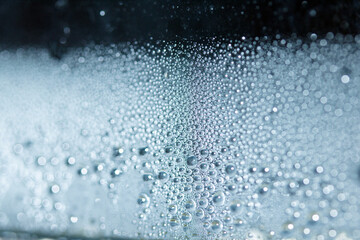 Obraz premium Blue Rain Bubbles Drops Running down a Window on a Wet Day Abstract Background