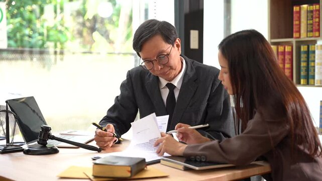 Legal Counsel: Close-up shot of a legal professional reviewing a document with a client in a professional office setting. The lawyer and the client are both focused on the papers.