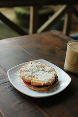 toast with cheese topping and a glass of coffee with milk on the table
