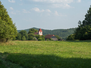 Summer view of old historical Bohemian village Zdirec Borejov with Church of St. James in in Baroque architectural style and green meadow and trees, Kokorin region, central Bohemia