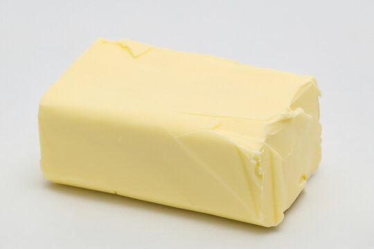 Piece of butter on background. Piece butter white background of lies. A white piece of butter lies on a white background. A block of butter on a lifestyle white background.