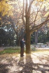 Obraz premium 冬の公園で散歩する中年女性と黄色いイチョウの木の風景