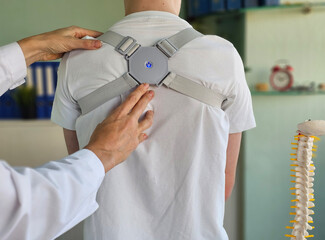 A medical professional adjusts a posture correction device on a patient back in a clinical