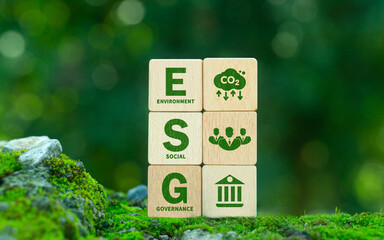 Green ESG icon on wooden block. Environment, social and governance concept. Net zero greenhouse gas emissions for a sustainable global environment. On a green forest background.