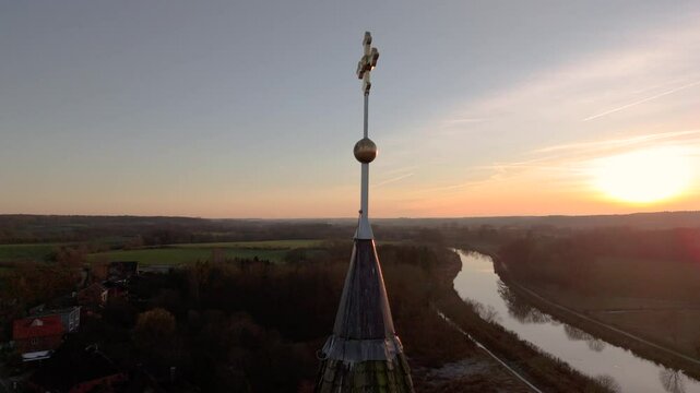 Drohne umkreist Kirchturmkreuz im Sonnenuntergang, episches Lichtspiel