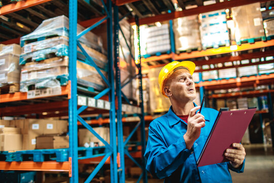Warehouse supervisor with hard hat checking inventory with clipboard
