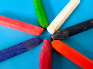 Colored pencils and crayons are on a blue background