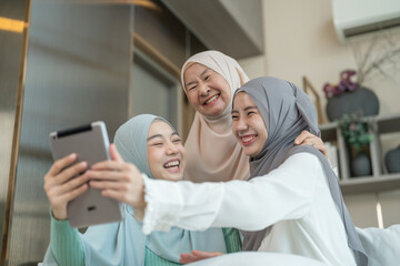 joyful muslim women family in hijab relax in the living room,using digital tablet communicate to family