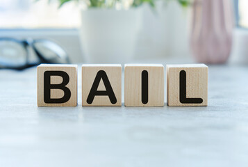 word BAIL on wooden cubes on blue background. the inscription on the cubes is reflected from the...