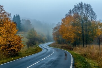 Naklejka premium Scenic curved road through misty autumn forest with colorful foliage.