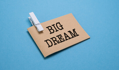 Cardboard with the text BIG DREAM pinned to a blue background. Isolated on a blue background.