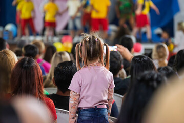 Niña de espalda en el público de un espectáculo familiar