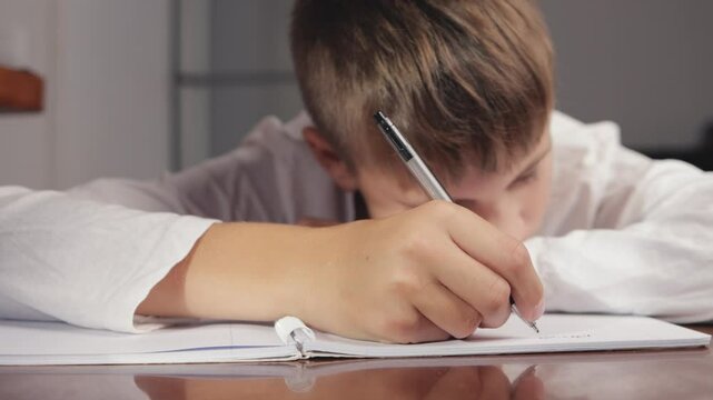 Young student focusing intently on writing in a notebook, showcasing commitment to learning and personal growth through dedicated study efforts