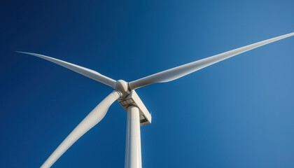 A close-up view of a white wind turbine against a clear blue sky, showcasing the blades and supporting structure.