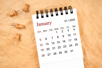 January 2025 white desk calendar with wooden thumbtack on old  crumpled paper.
