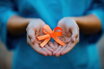 A Pair of Hands Holding an Orange Ribbon Symbolizing Hope, Awareness, and Support for Important Causes in a Natural Outdoor Setting