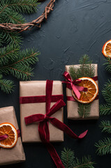 Christmas decoration and wrappung gifts on black background flat lay top view eco sustainable composition with pine branches and dried oranges copy space cute ribbons