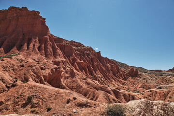 Fototapeta premium Fairytale canyon with red rocks. Picturesque Skazka Canyon on southern shore of Issyk-Kul lake, Kyrgyzstan. Travel destination, landmark Kirgiziya. Summer natural park landscape