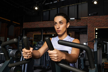 Dedicated woman exercises intensely in a modern gym environment, striving for fitness goals.