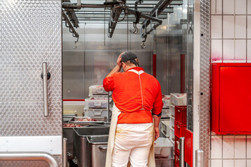 Butcher touching head entering cold storage room in slaughterhouse