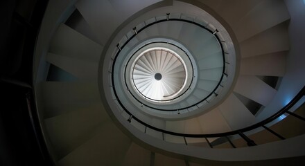 Fototapeta premium Spiral staircase leading to light in modern architecture