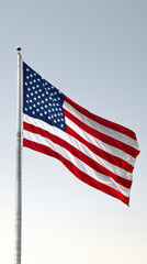 Obraz premium The image features the American flag waving against a clear sky, showcasing its iconic red, white, and blue colors.
