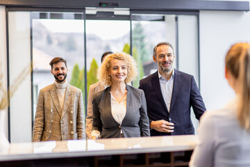 Group of business people arriving in a hotel for a business conference walking towards the...